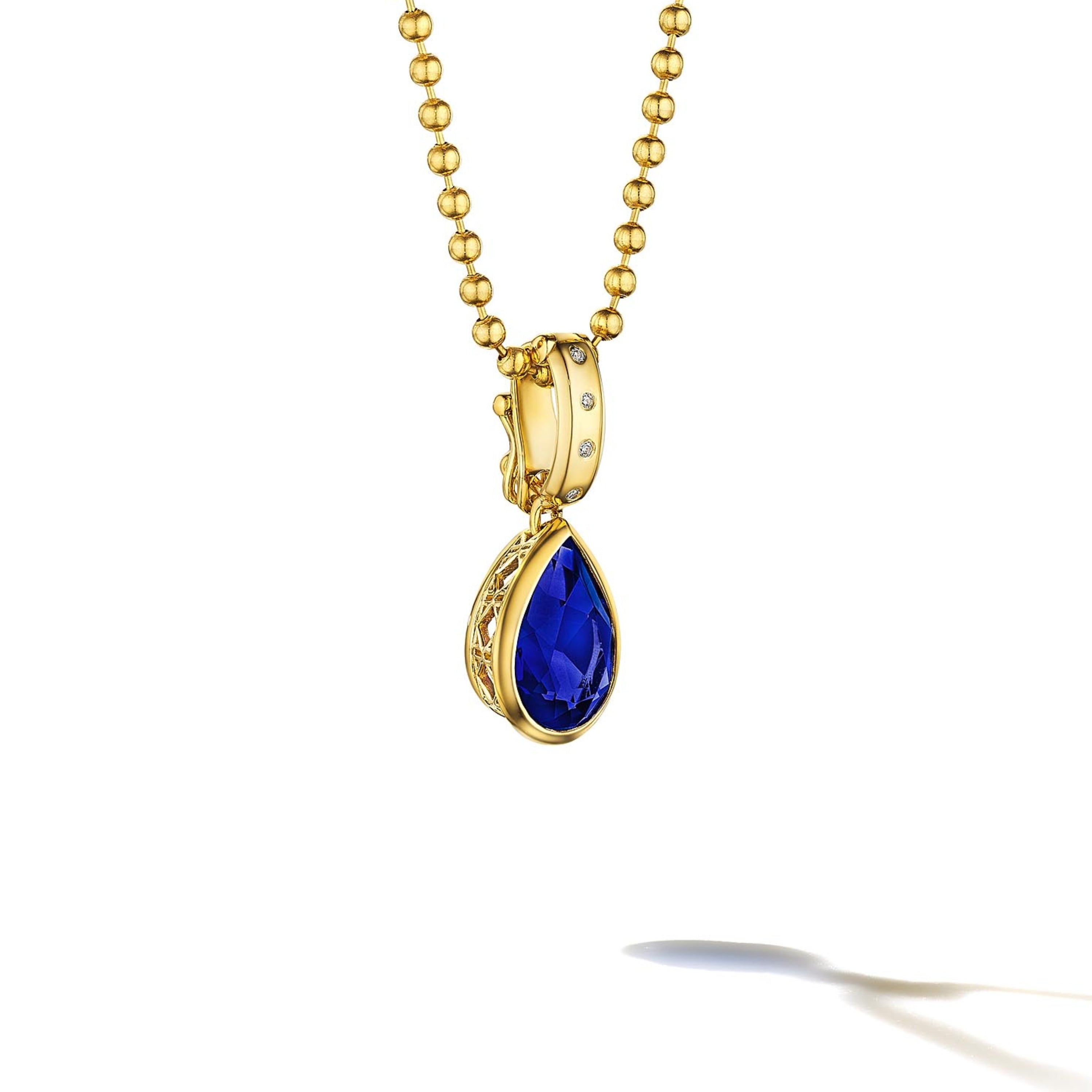 MoAnA LUU Dlo pear-shaped blue sapphire pendant in 18K yellow gold with diamonds, featuring a cane-woven frame inspired by traditional Caribbean fish traps, reflecting the house’s vision of Creole-inspired fine jewelry crafted in New York.
