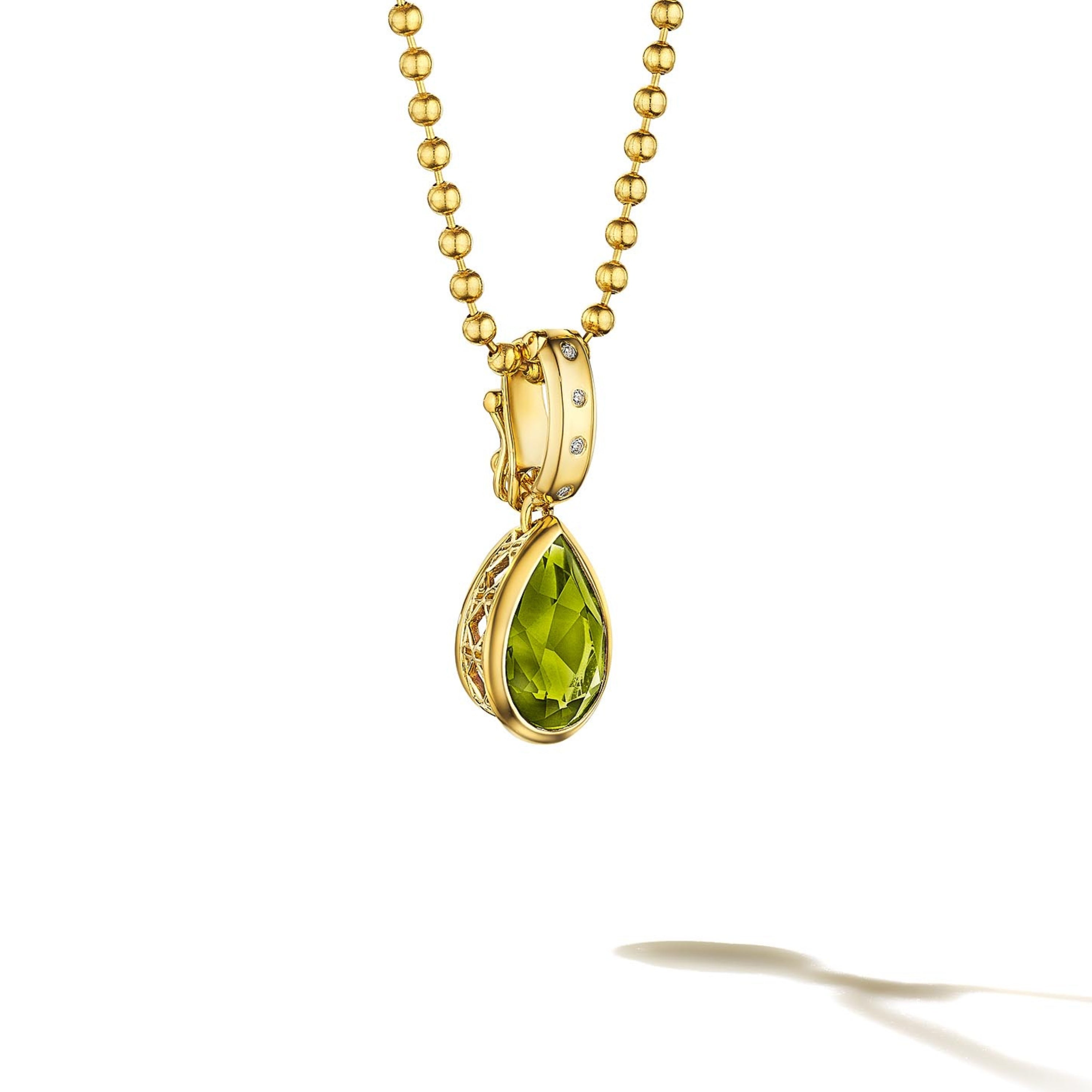 MoAnA LUU Dlo pear-shaped peridot pendant in 18K yellow gold, featuring a cane-woven frame inspired by traditional Caribbean fish traps, reflecting the house’s vision of Creole-inspired fine jewelry crafted in New York.