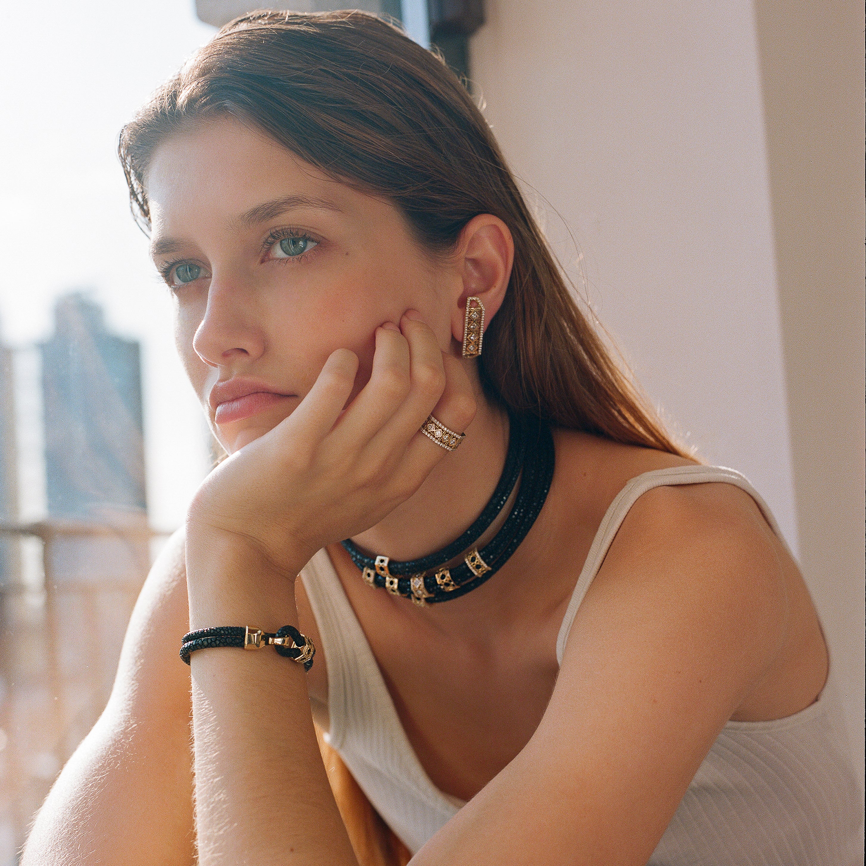 MoAnA LUU fine jewelry worn on model, featuring Abyss stingray leather chokers and bracelet with 18K yellow gold elements, paired with Doudou diamond earrings and ring inspired by Caribbean fish traps.