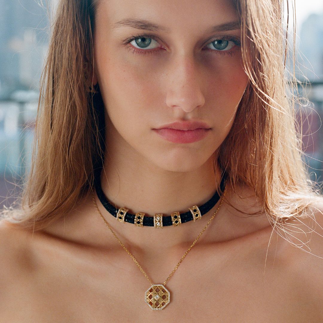 MoAnA LUU fine jewelry worn on model, featuring Abyss stingray leather choker with gold and diamond elements, paired with Doudou octagonal pendant necklace in 18K yellow gold inspired by Caribbean fish traps.