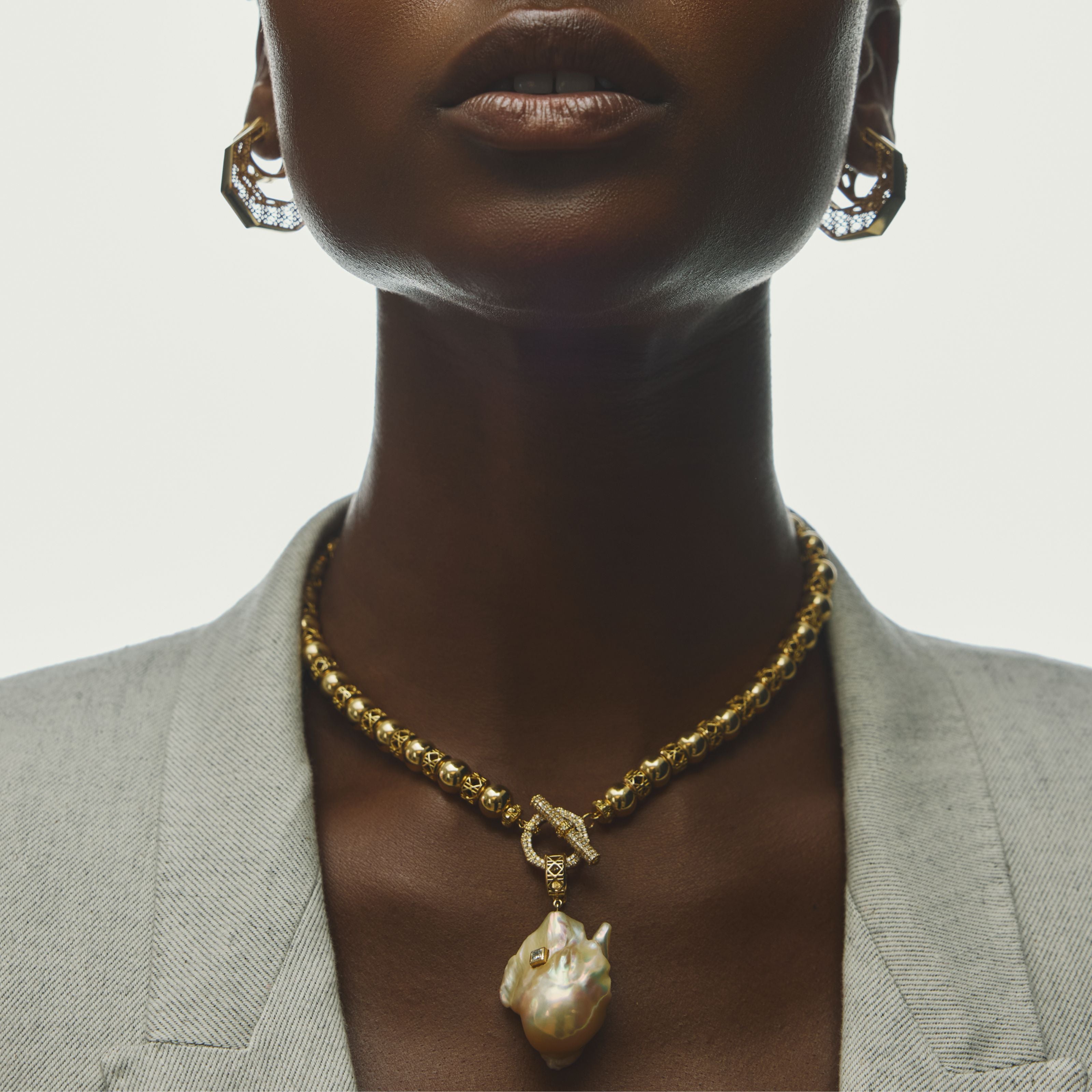 MoAnA LUU 18K yellow gold fine jewelry worn model, featuring Yva beads in 18K gold with Abyss South Sea baroque pearl amulet and sculptural Doudou gold earrings inspired by Creole design.