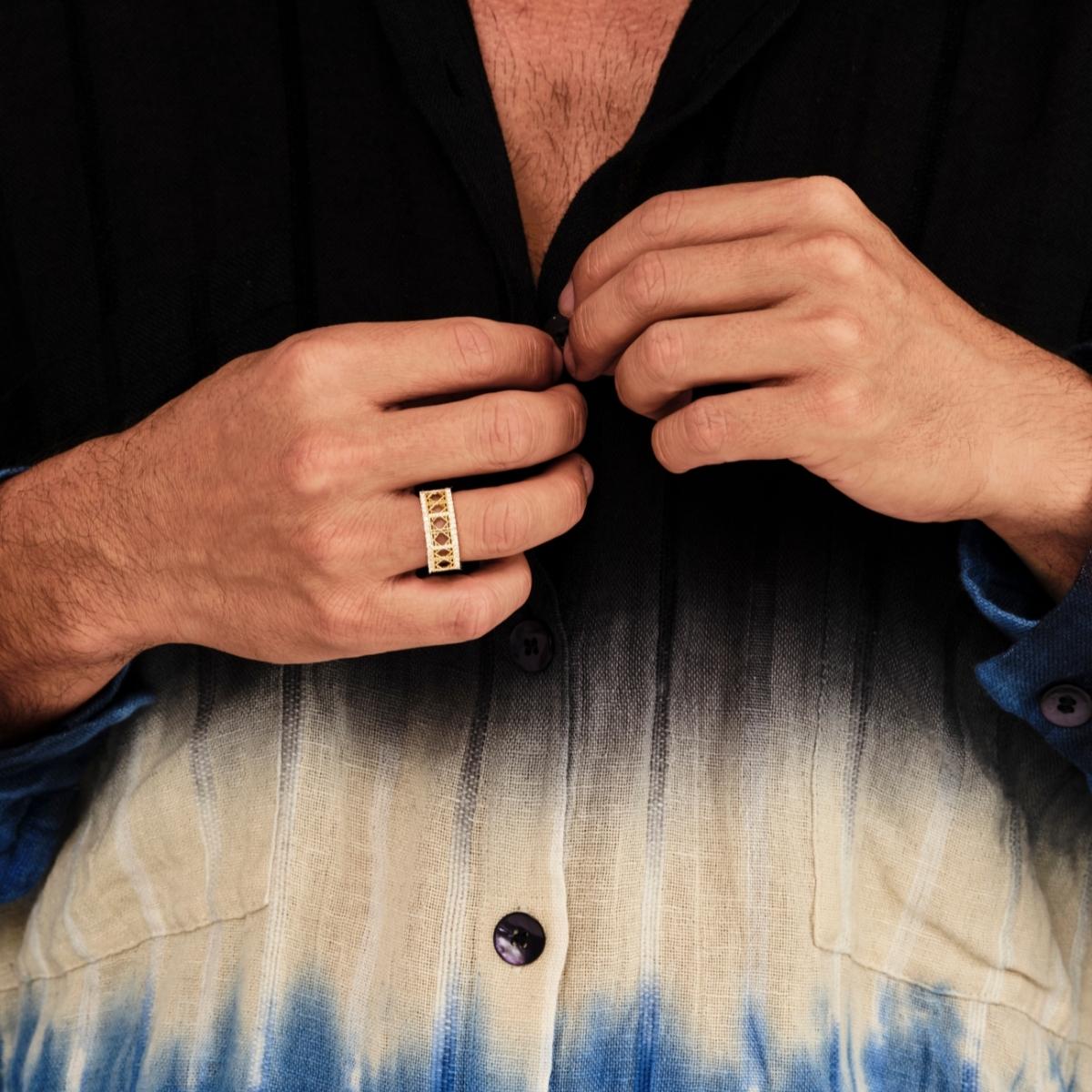 Model wearing MoAnA LUU Doudou band ring in 18K yellow gold with pavé boarders, featuring geometric woven openwork design inspired by Caribbean fish traps.