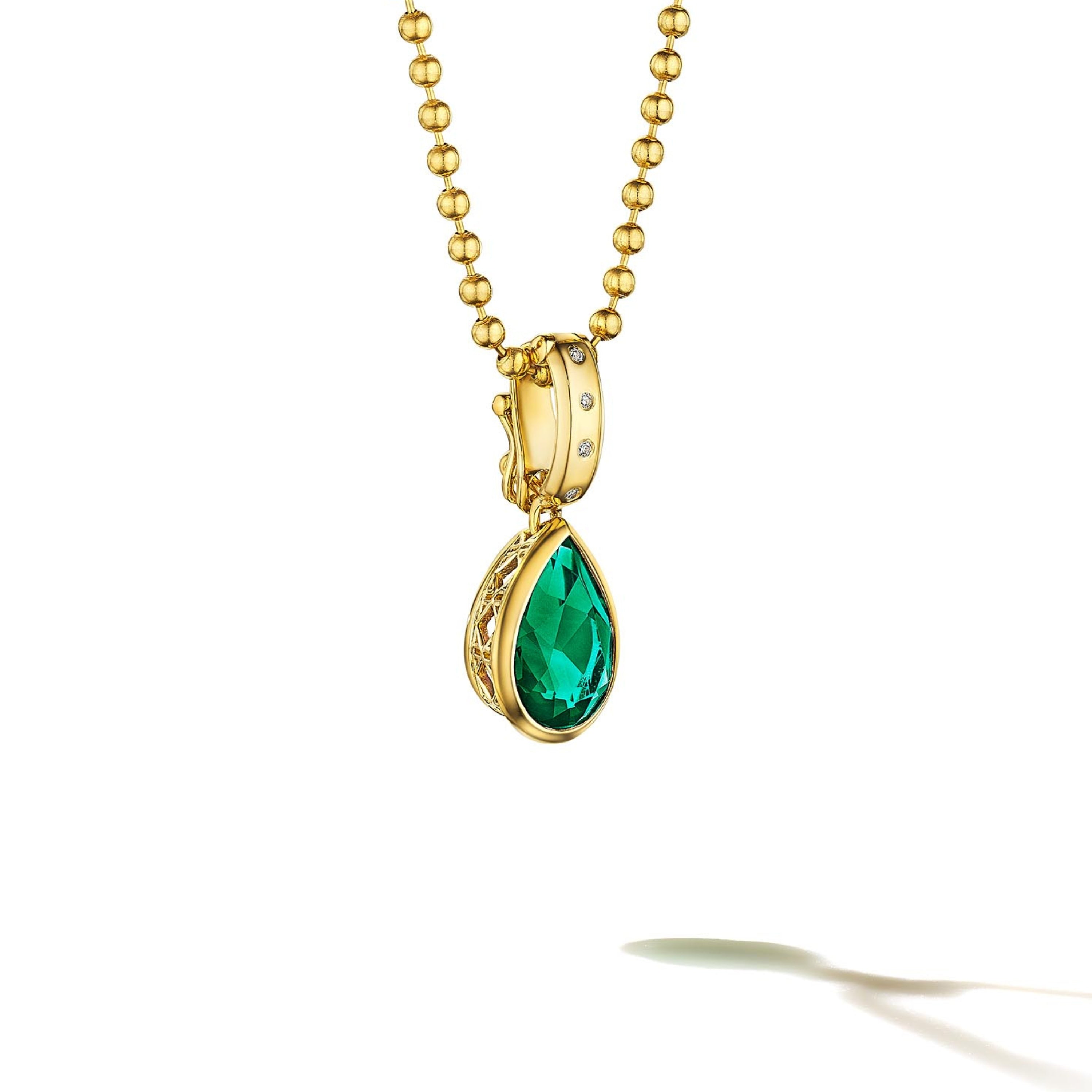 MoAnA LUU Dlo pear-shaped emerald pendant in 18K yellow gold, featuring a cane-woven frame inspired by traditional Caribbean fish traps, reflecting the house’s vision of Creole-inspired fine jewelry crafted in New York.
