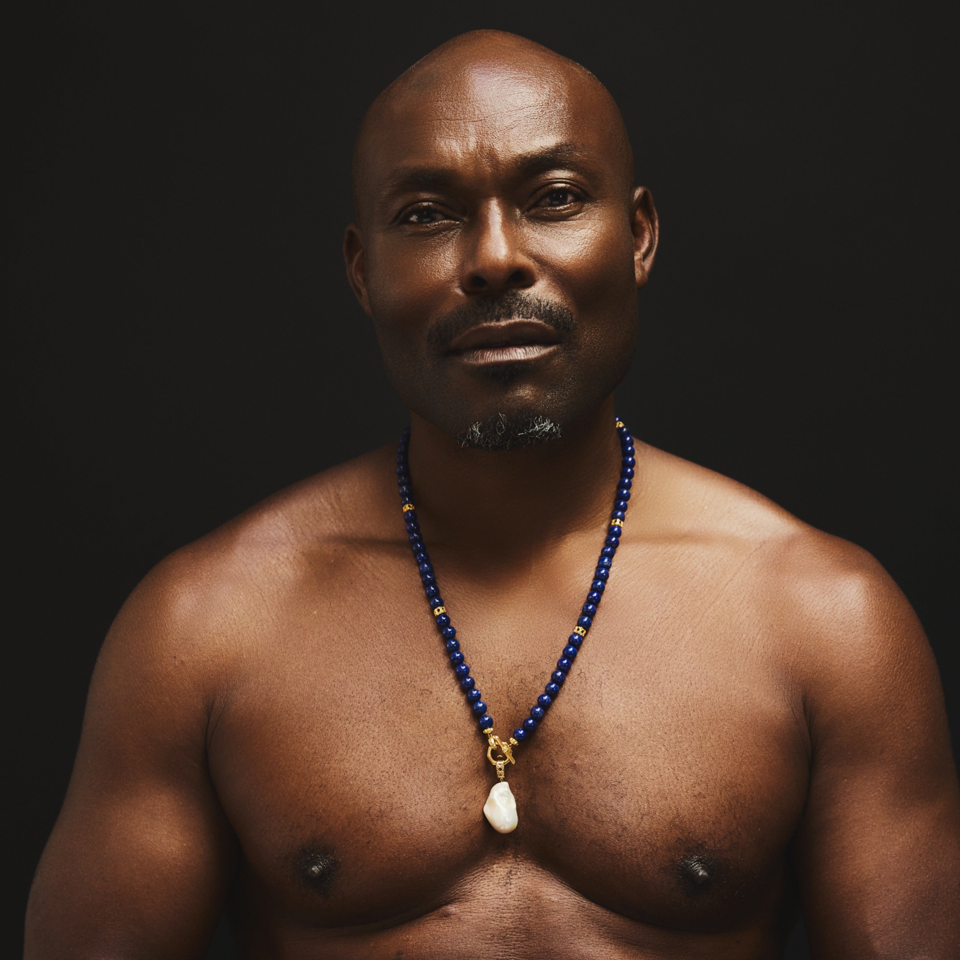 MoAnA LUU fine jewelry worn by Jimmy Jean Louis, featuring Yva bead necklace in lapis lazuli with 18K yellow gold toggle inspired clasp and cane woven gold beads inspired by Caribbean fish traps. 