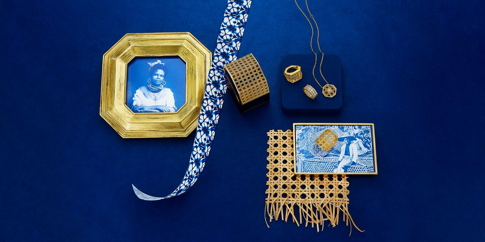 MoAnA LUU jewelry styled on a deep blue background, featuring gold pieces alongside archival Caribbean portraits, woven cane elements, and patterned textiles.