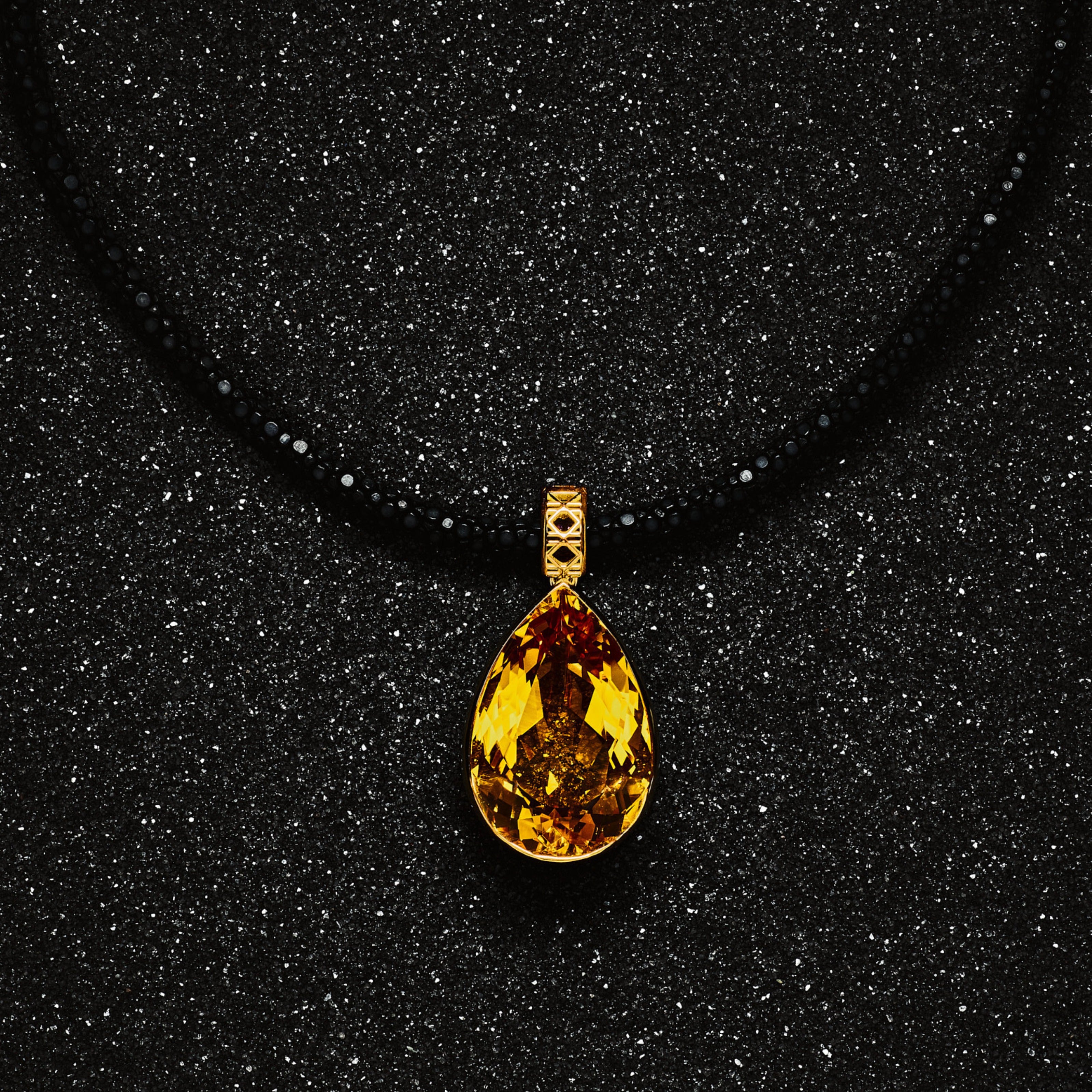 MoAnA LUU Maxi Dlo pear-shaped citrine pendant in 18K yellow gold on a black stingray leather necklace, featuring a sculptural cane-woven bail and openwork basket inspired by Caribbean fish traps.