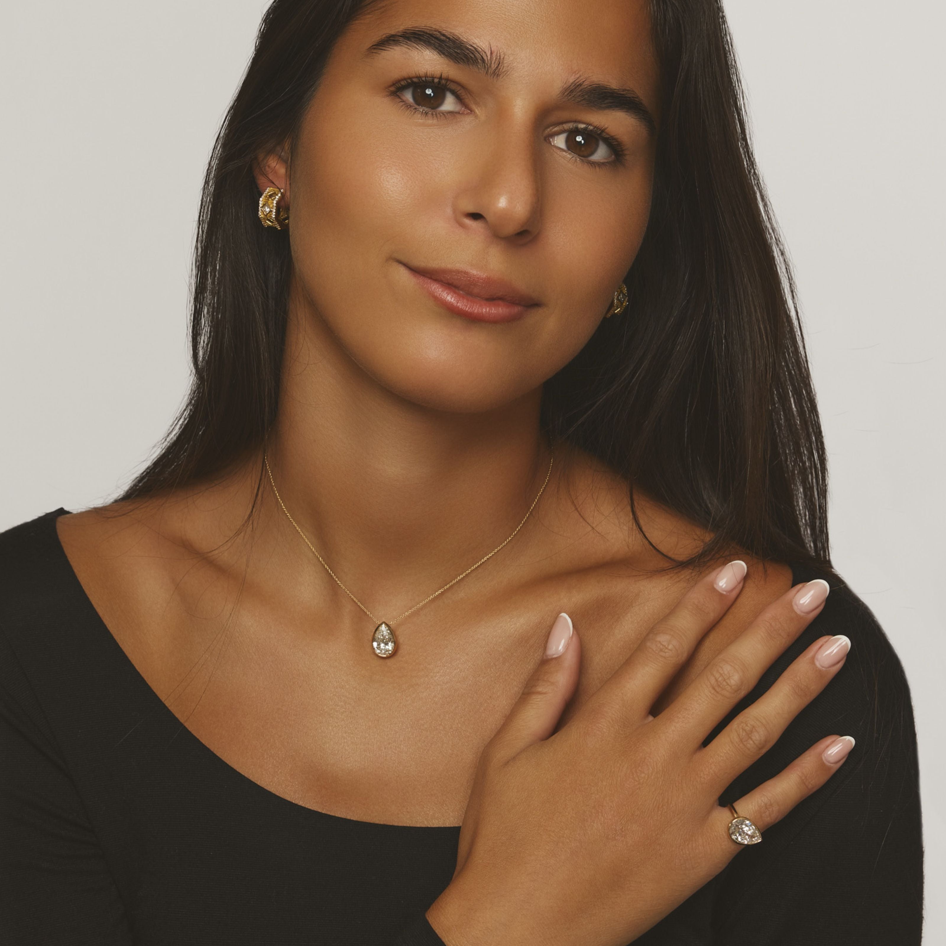 MoAnA LUU Dlo pendant and Dlo ring worn on hand, showcasing sculptural pear-shaped gem and cane woven design inspired by Caribbean heritage.