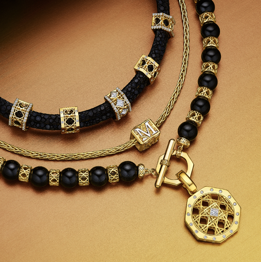 MoAnA LUU layered necklaces in 18K yellow gold featuring Yva onyx bead necklace, Abyss stingray leather choker with diamond-set beads, Foyal monogram charm, and Doudou geometric pendant with diamond center inspired by Caribbean fish traps.