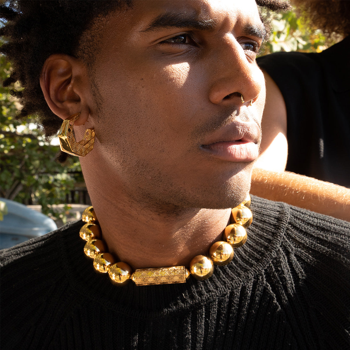 MoAnA LUU Doudou hoop earrings in 18K yellow gold, featured with bead necklace worn by male model.